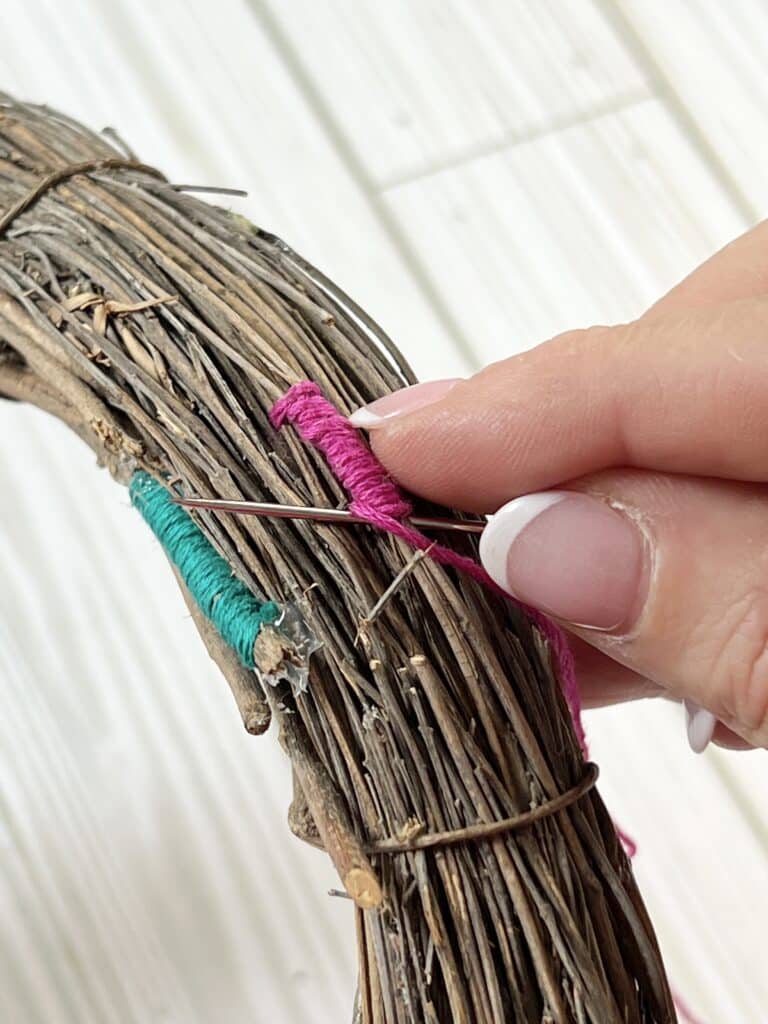 Adding pink embroidery thread to the grapevine wreath.