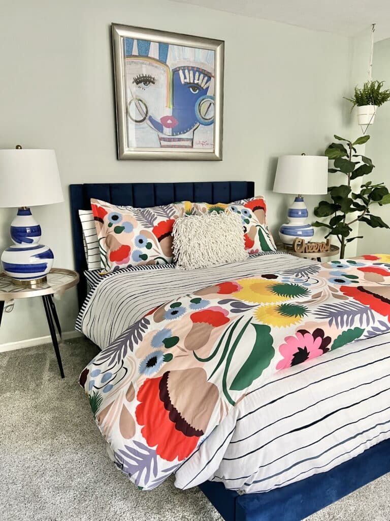 A colorful guest room with multi colored bedding and vibrant wall art.
