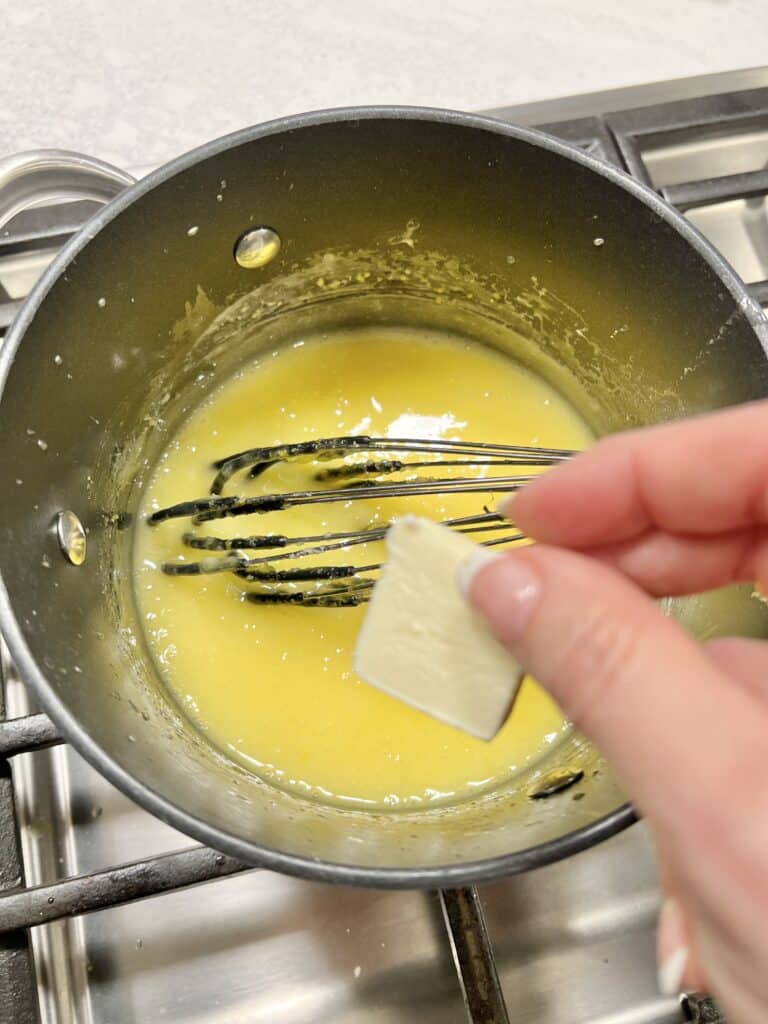 Ingredients combined into a saucepan on the stove and adding pats of butter.