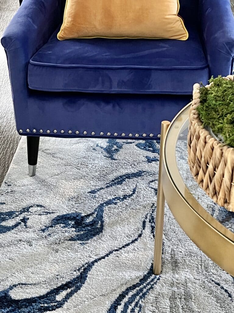 glamorous decorating ideas include bold colors like this cobalt blue velvet chair, gold pillow, and blue and white abstract rug.