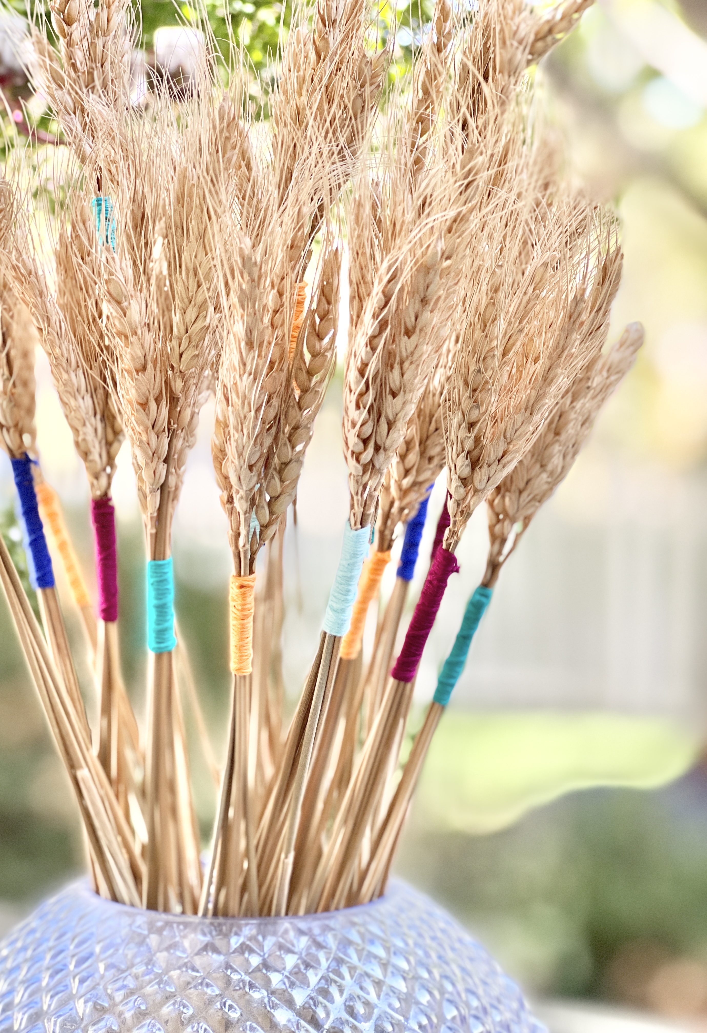 A hobnail vase holding thread wrapped wheat bundles is an easy Thanksgiving wheat decor idea.