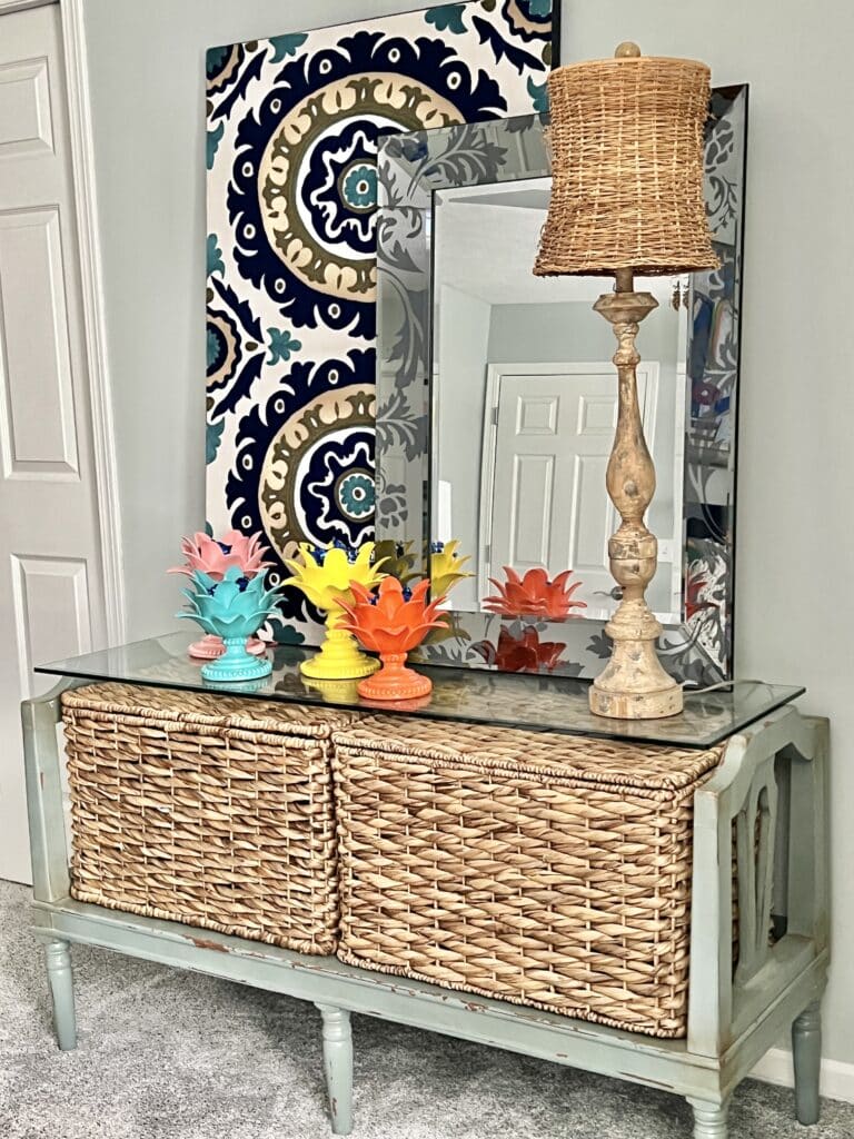 A dresser created from a bench, a piece of glass, and two baskets holds brightly colored lotus blossoms.