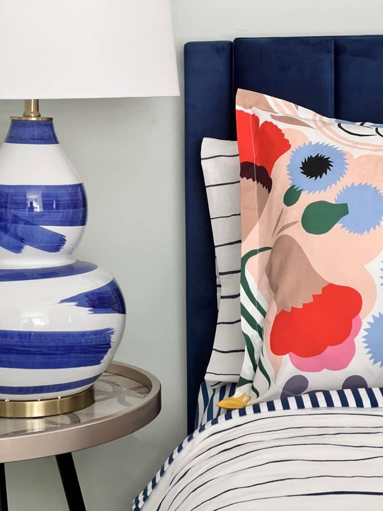 Layered bedding with various stripes and patterns create a comfy and cozy bed in the guest bedroom.