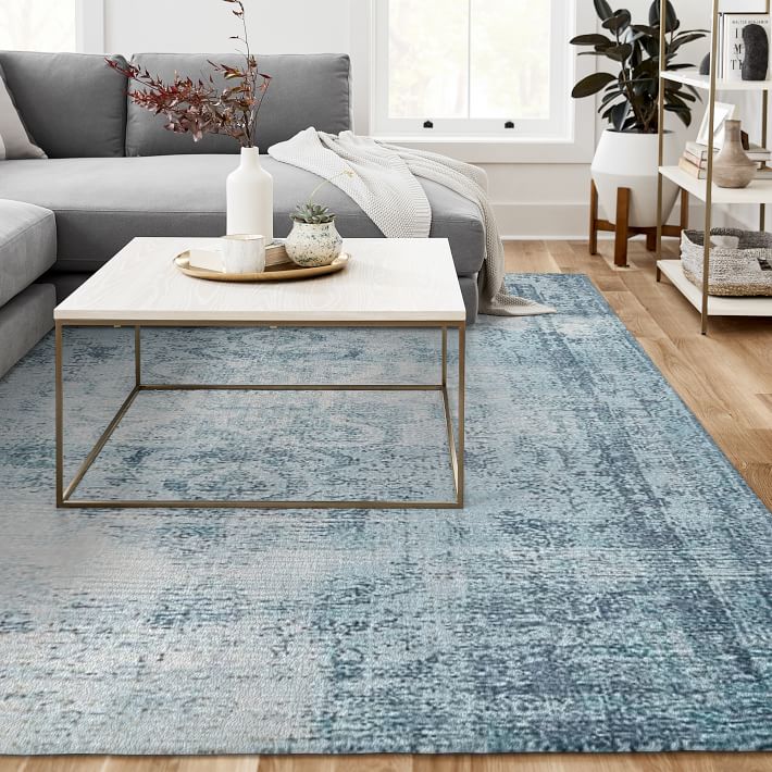 A muted old world style blue rug from West Elm under a coffee table.
