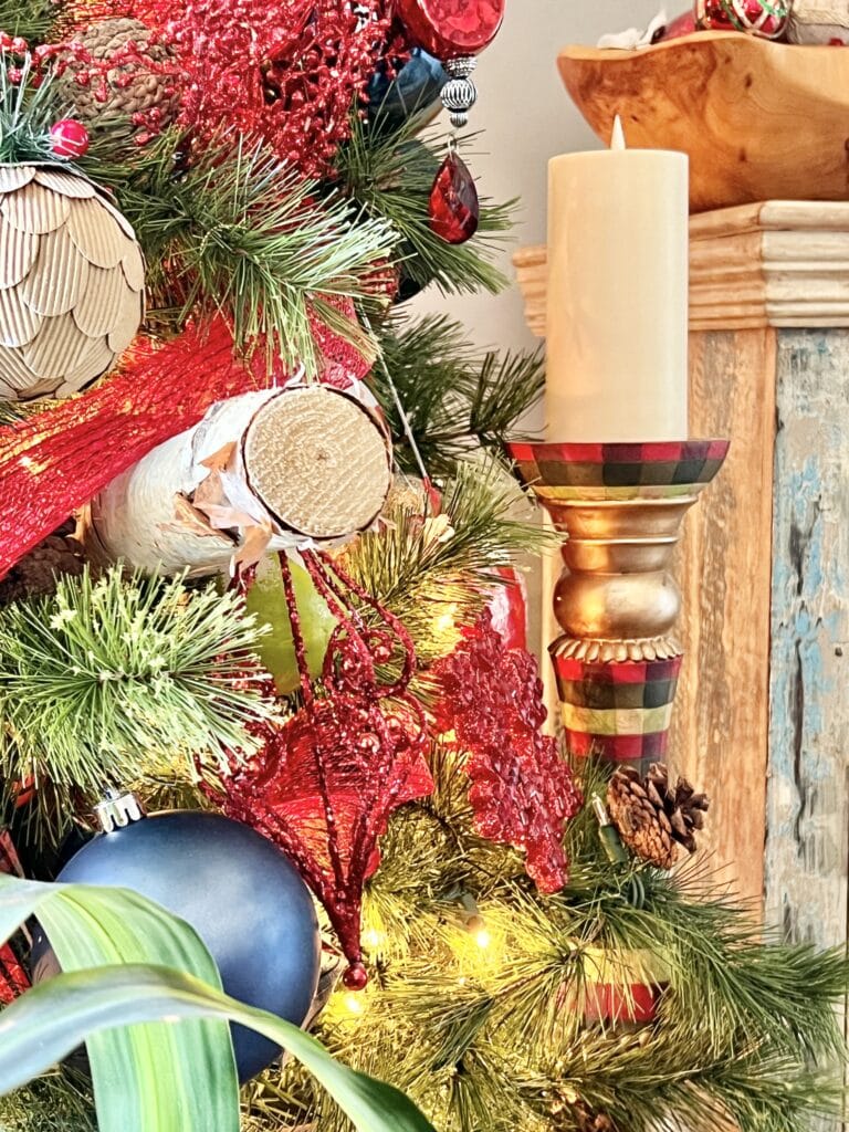 A plaid candle holder sitting beside the Christmas tree.