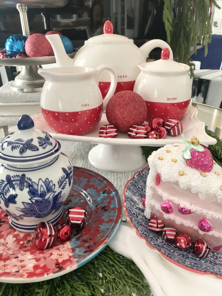 A red and white tea set sitting on top of a white cake stand.