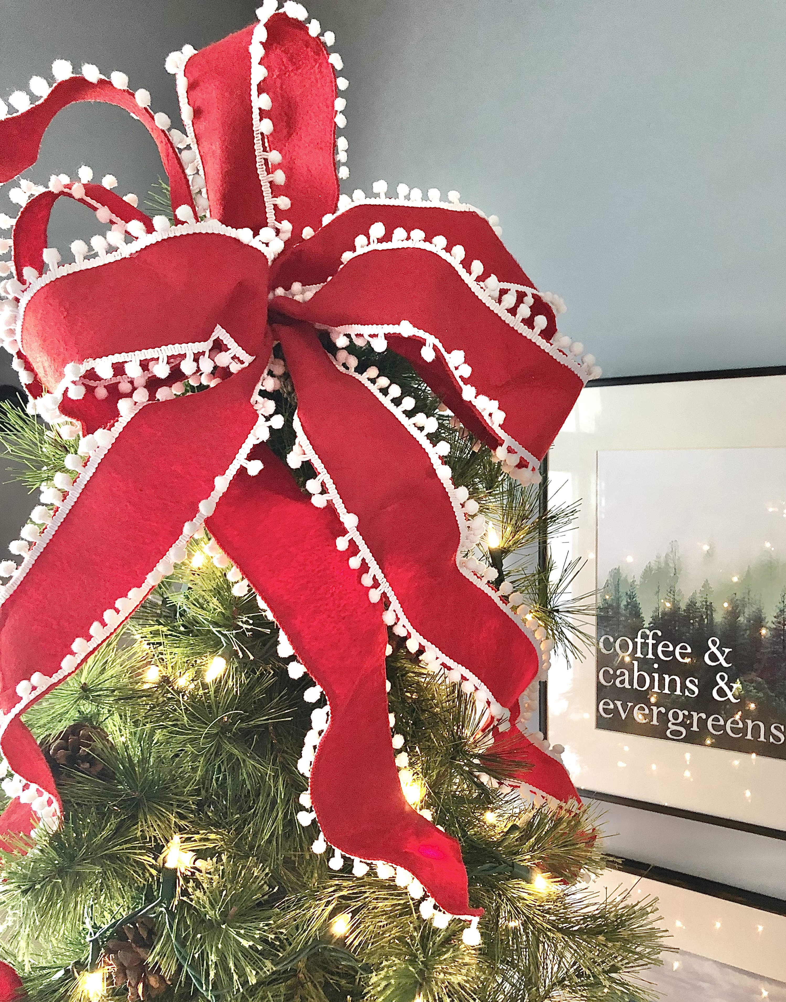 A red loopy bow on top of the Christmas tree.