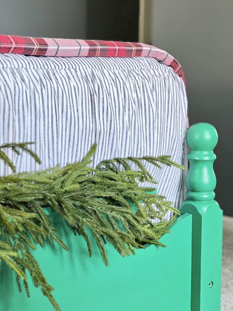 Green garland draped across the top of the painted footboard.