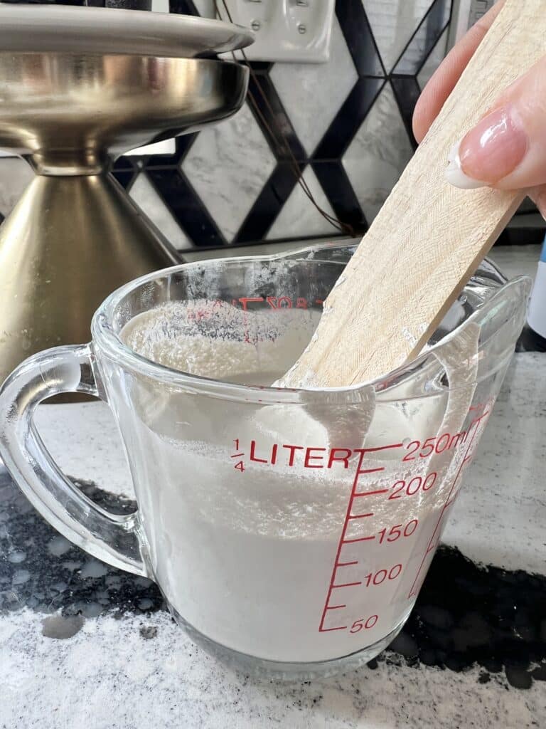 Mixing white paint with fabric softener and water for the painted jute rug.