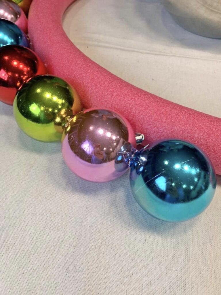 Christmas ornament wreath DIY: Christmas ornament balls glued to a pool noodle wreath form.