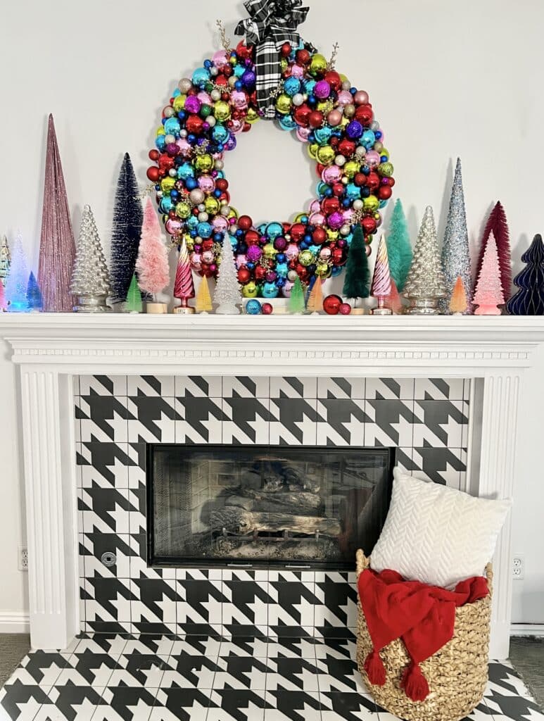 The remodeled fireplace surround and mantel decorated for Christmas with an ornament wreath and bottle brush trees.