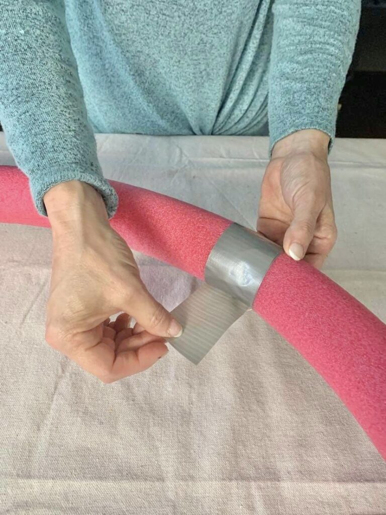Using duct tape to attach the ends of two pool noodles together.