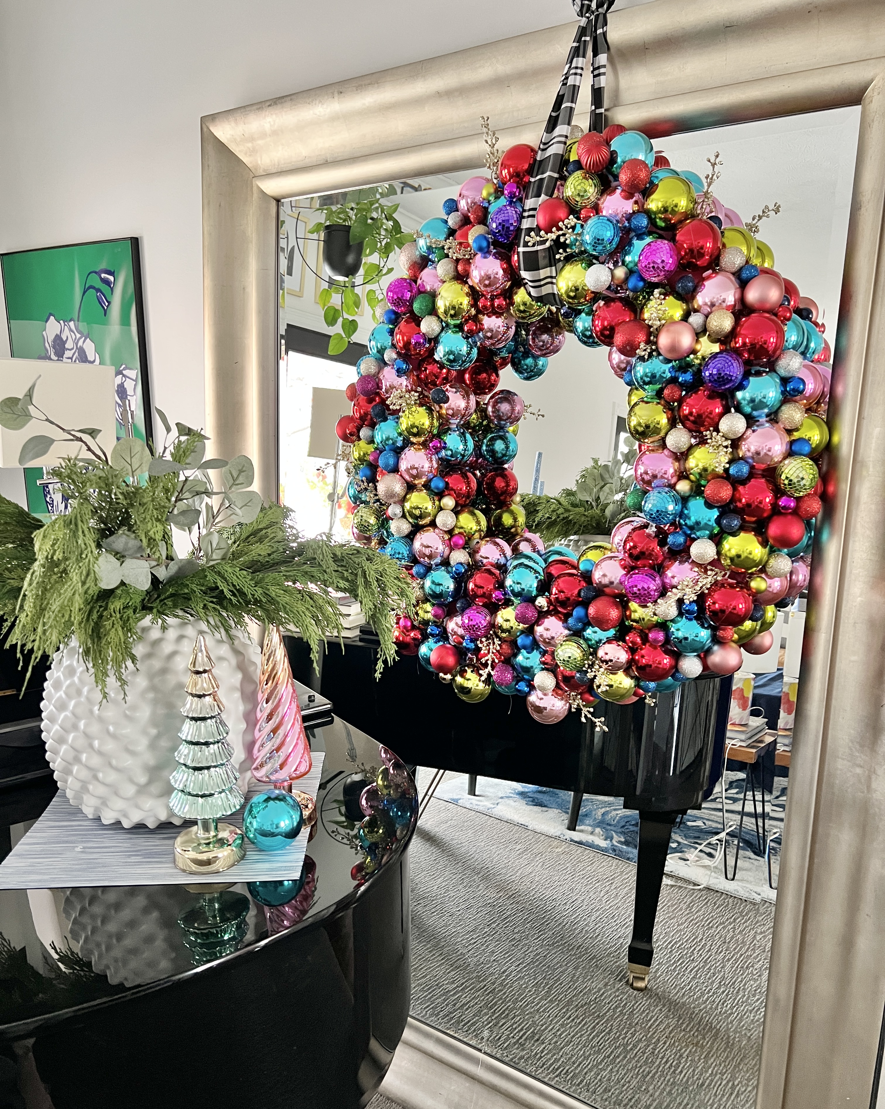 A Christmas wreath displayed on a large mirror.