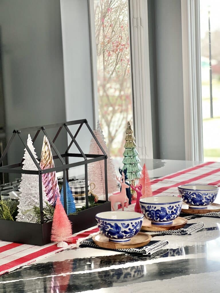 This Christmas centerpiece idea consists of a tabletop terrarium, various small trees, small reindeer and soup bowls.