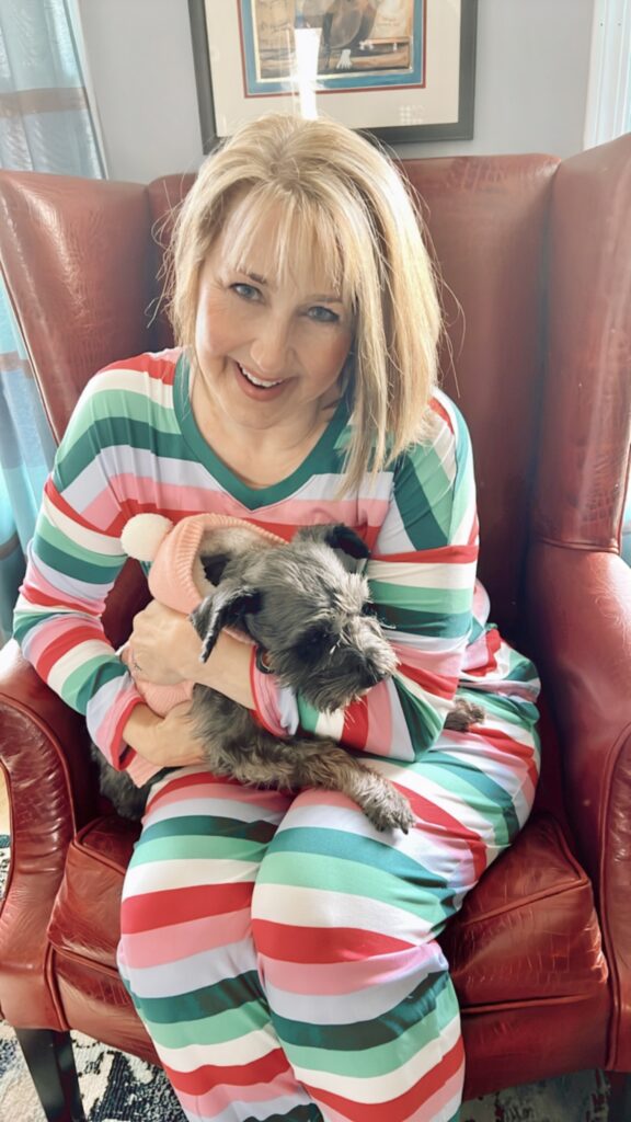 Missy in striped pajamas and holding a schnauzer dog.