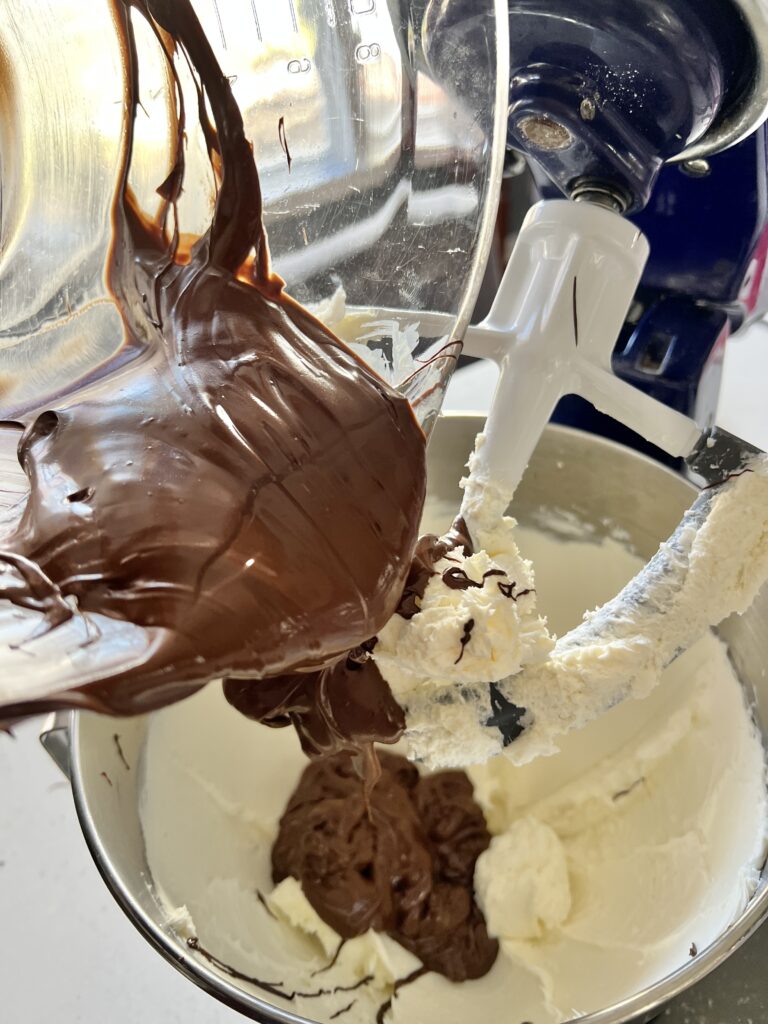 Adding melted chocolate to whipped cream cheese for this Christmas truffle recipe.