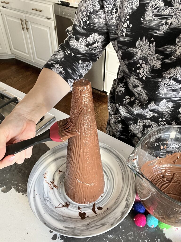 Brushing melted chocolate onto a styrofoam cone.