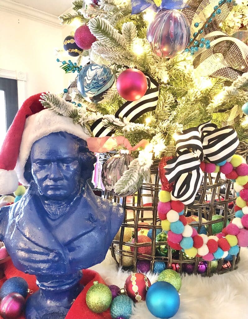 A painted blue Beethoven bust wearing a Santa hat.