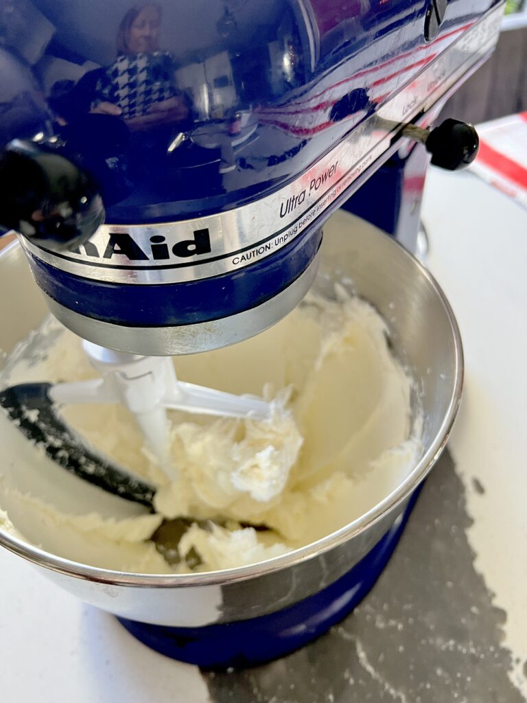 Beating cream cheese in an electric mixer.