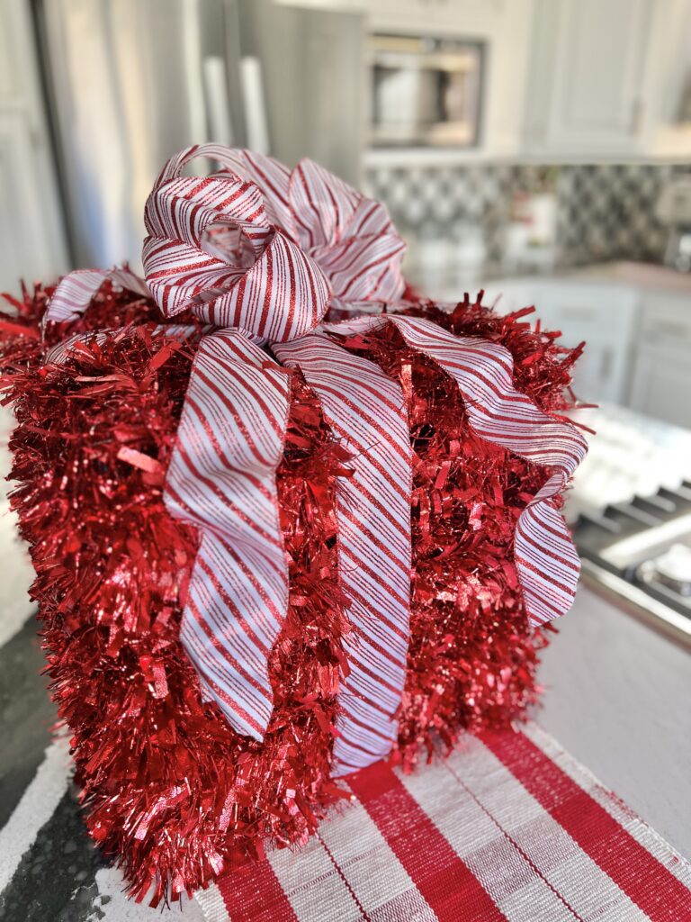 A DIY tinsel Christmas gift present sitting on a kitchen island.