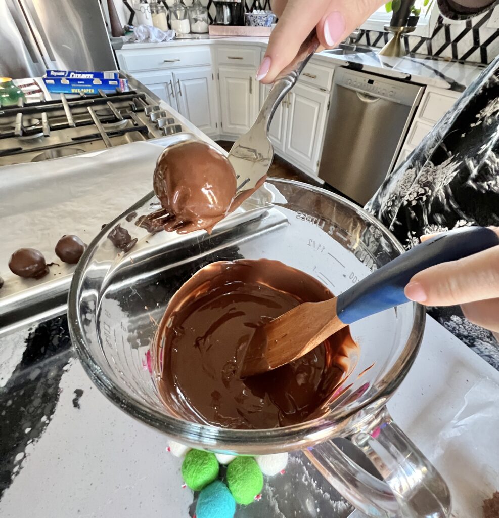 Dipping the chocolate balls in melted almond bark for this Christmas truffle recipe.