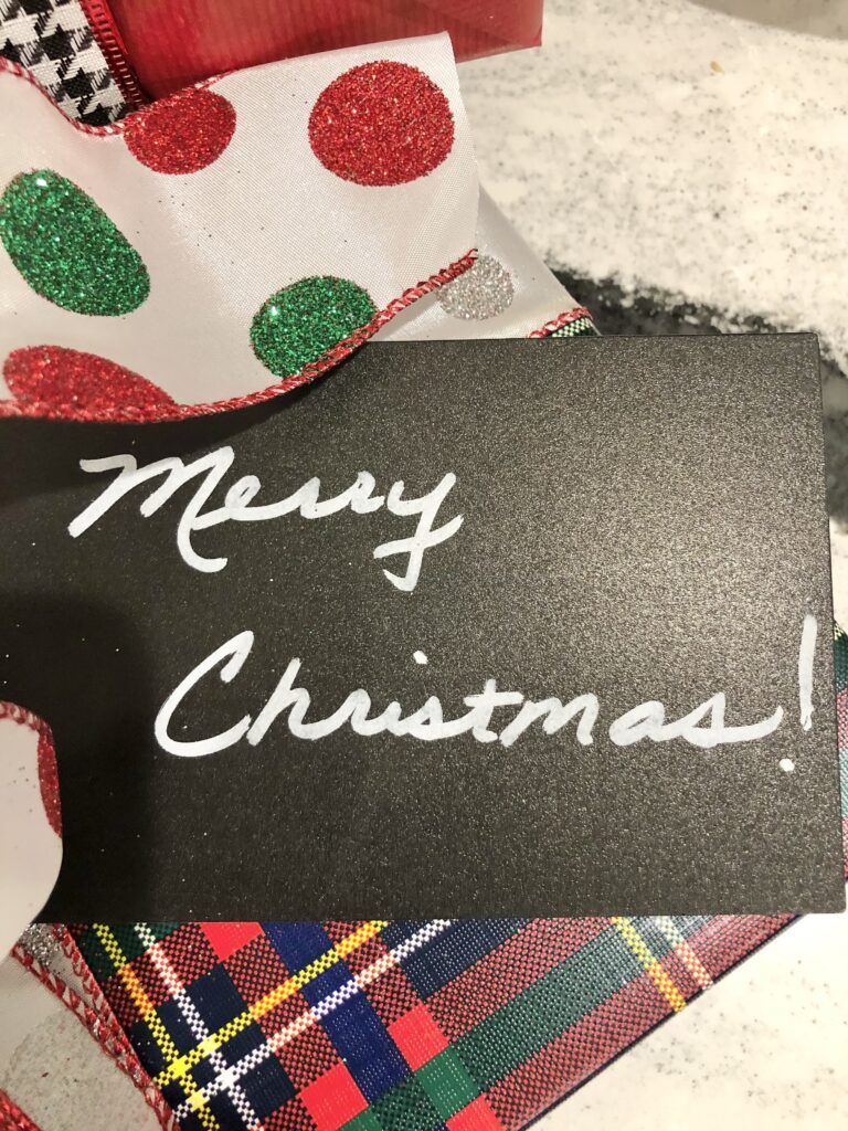 The words "Merry Christmas" written on a black gift tag.