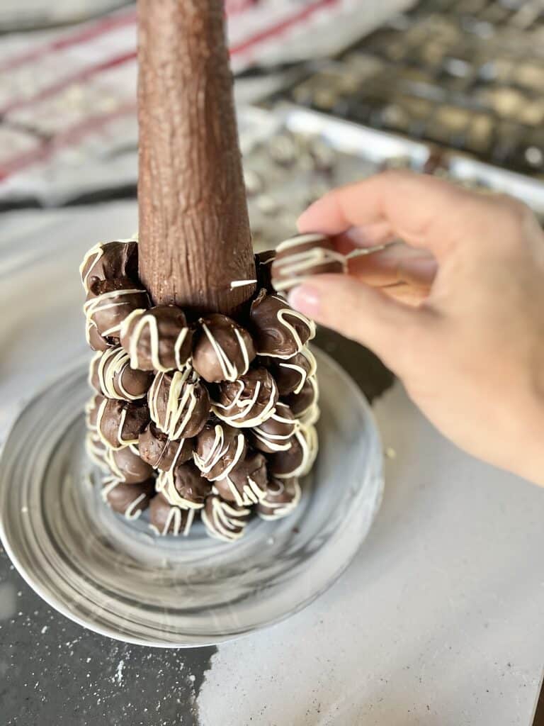 Stacking layers of Christmas truffle recipe balls onto a styrofoam cone.