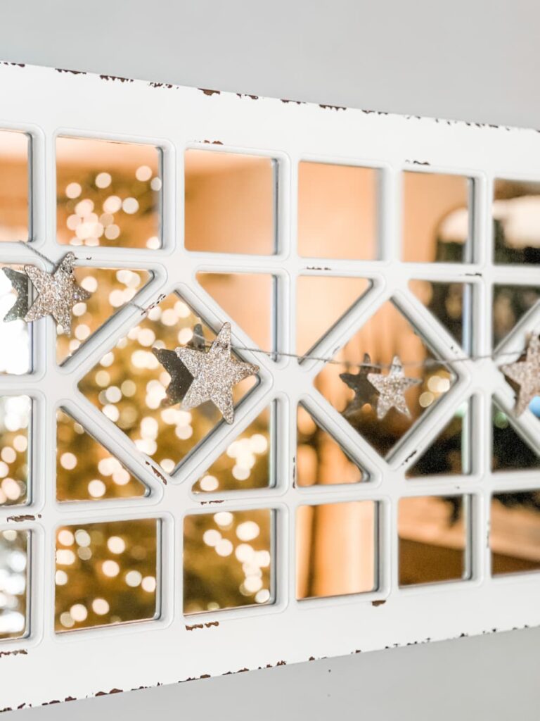 A vintage window draped with a gold star garland at Saved from Salvage.