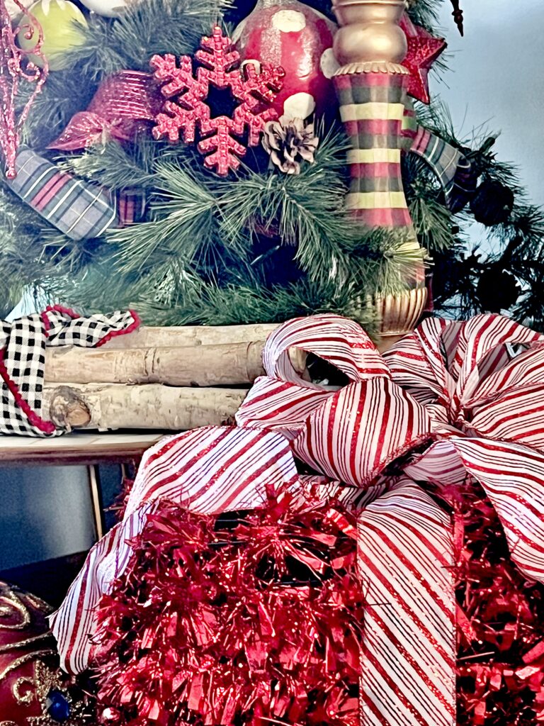 A tinsel Christmas gift package sitting beside a Christmas tree.