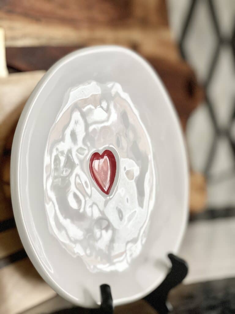 A white plate with a red heart sitting on a black easel is good kitchen Valentine's Day home decor.