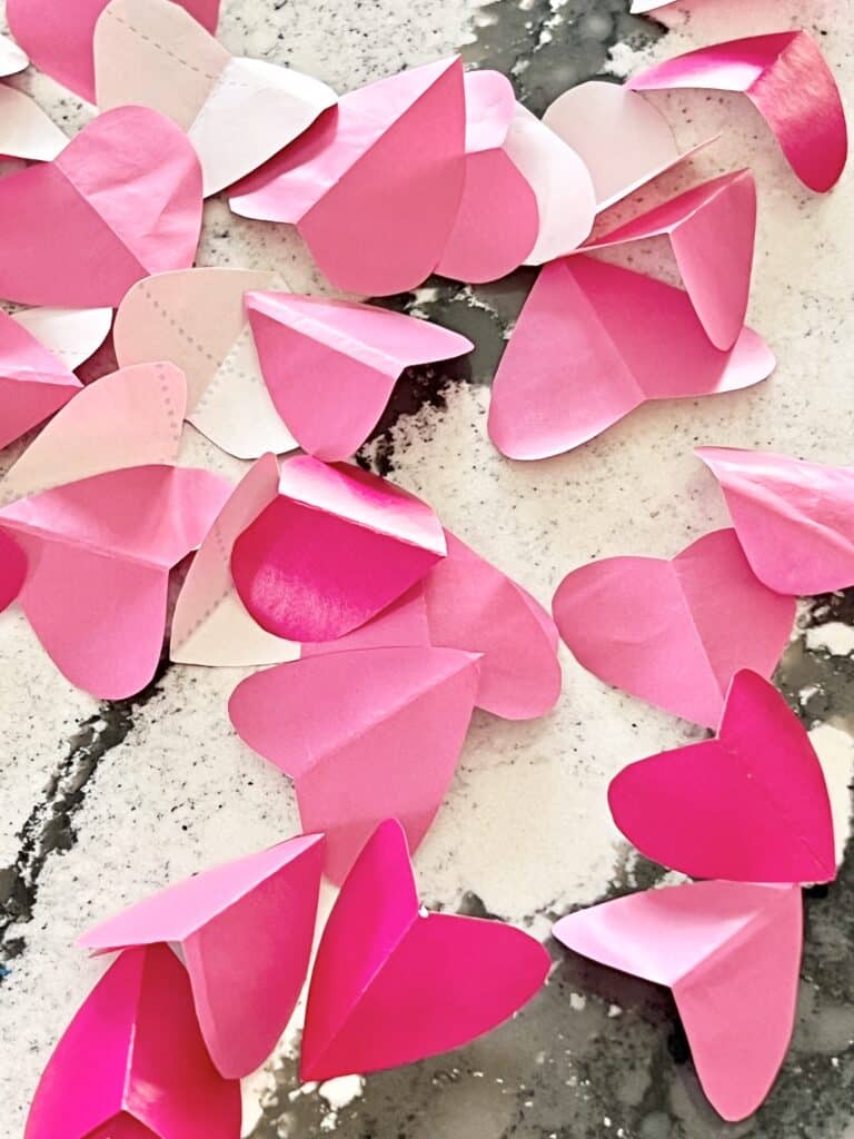Pink paper hearts strewn on a countertop.