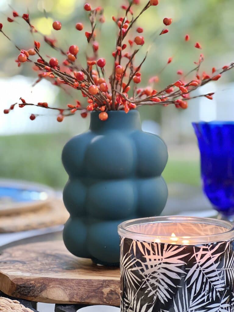 A blue vase filled with orange pip berries.