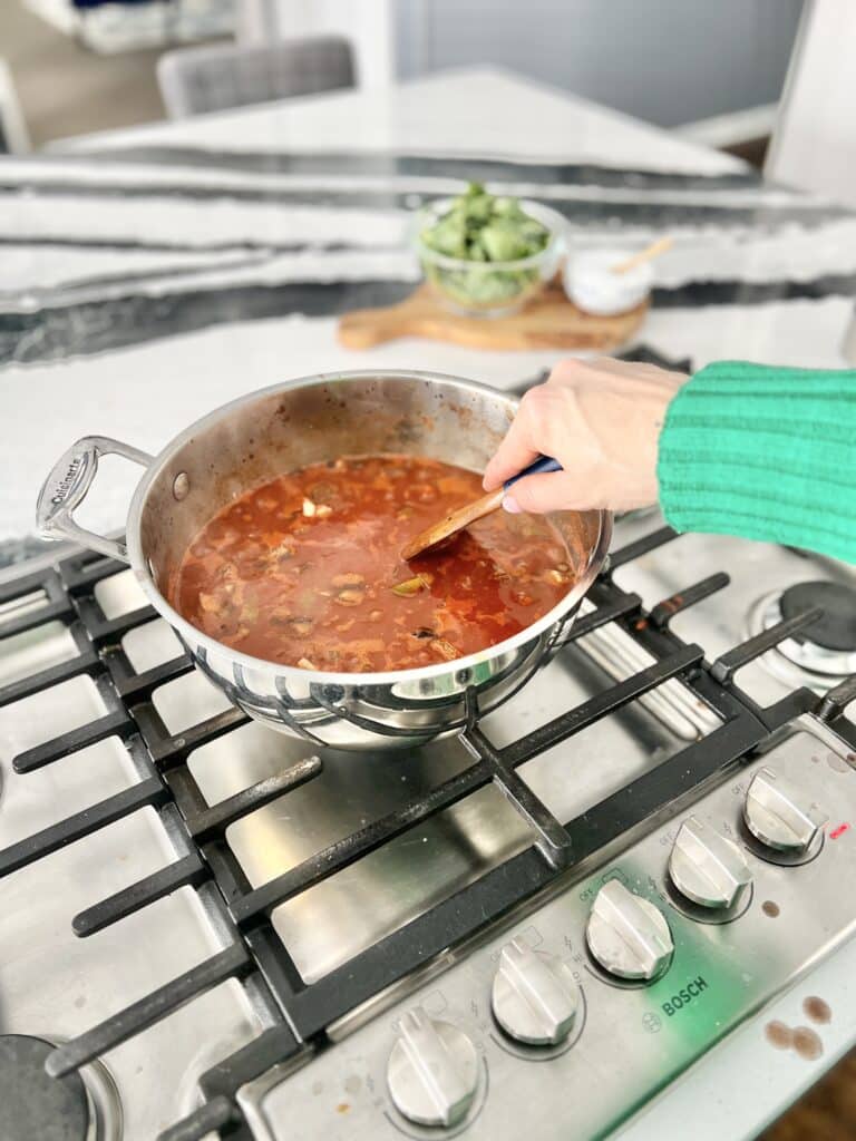 Stirring a stovetop pot of healthy winter vegetable soup.