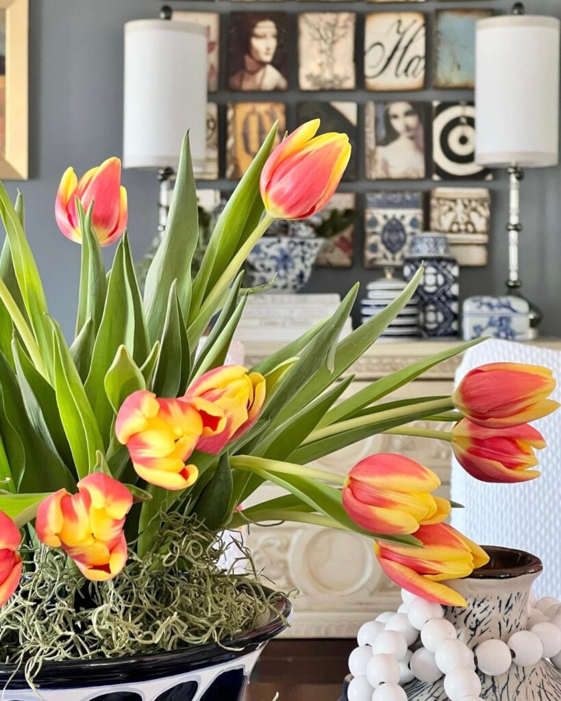 Orange and yellow tulips in a centerpiece on a dining room table is fresh colorful home decor.