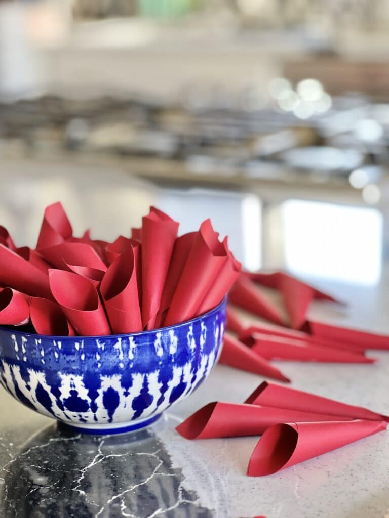 A bowl full of red paper cones to be glued on the cardboard heart.