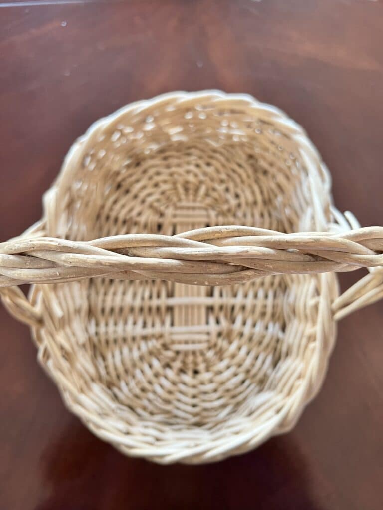 A light colored wicker basket with a handle.