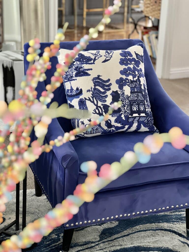 A blue and white chinoiserie pillow sitting in a cobalt blue chair.