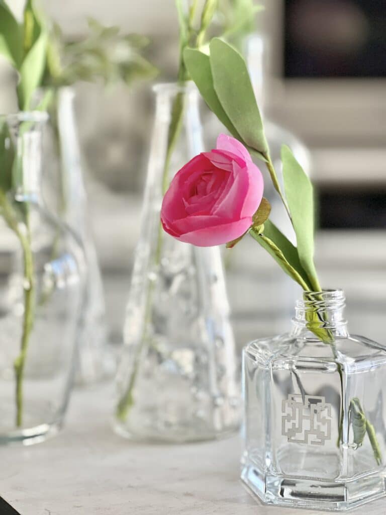 A pink flower in a short glass vase. has dramatic impact in this flower display.