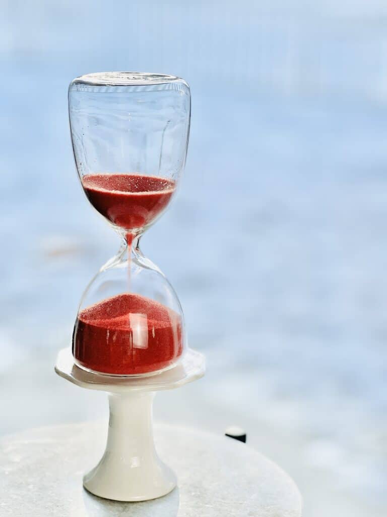 An hourglass filled with sand and sitting against a backdrop of white snow.