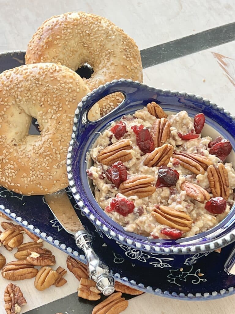 A Cranberry Pecan Bagel Spread on a tray with two sesame bagels.