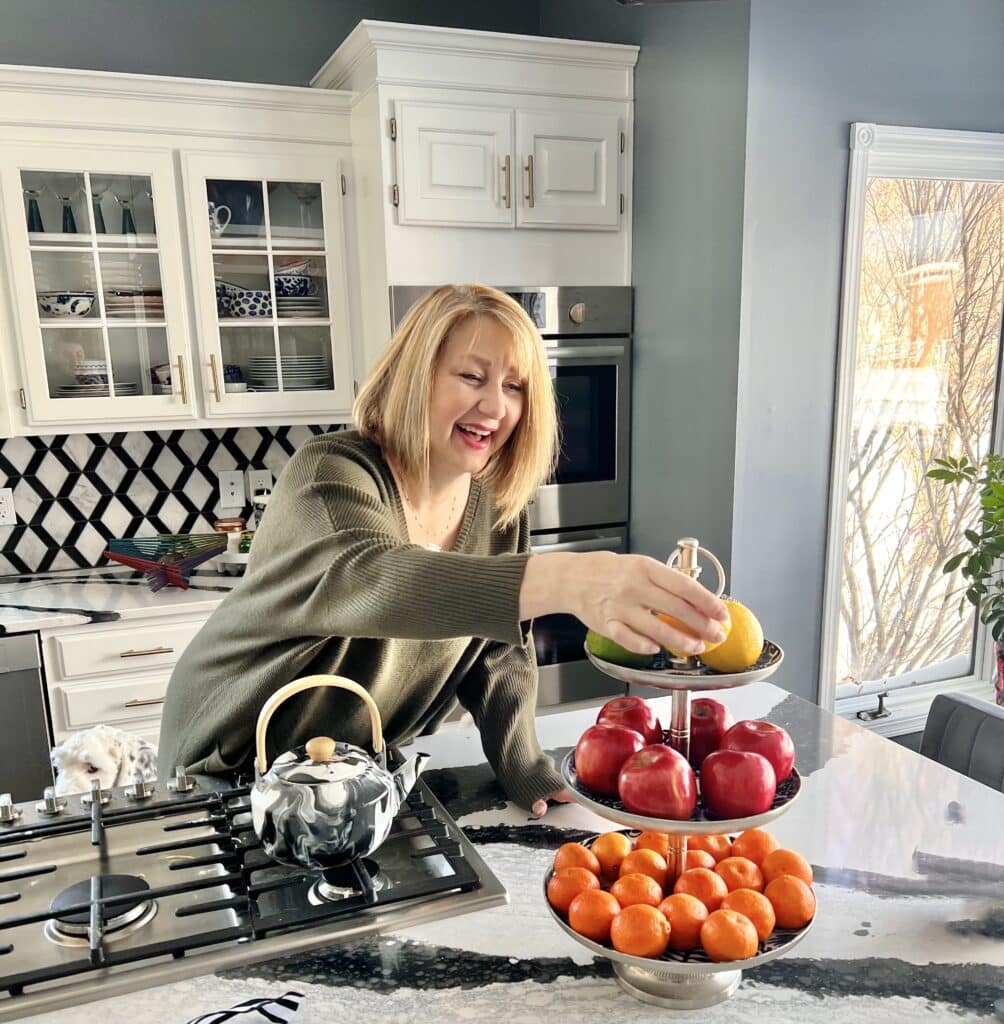 Missy arranging fruit on a tiered tray in the kitchen.