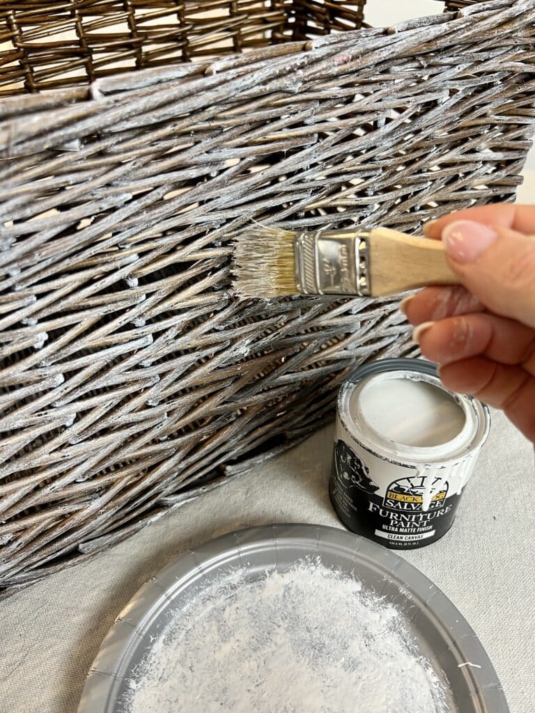 Dry brushing a wicker basket with white paint.