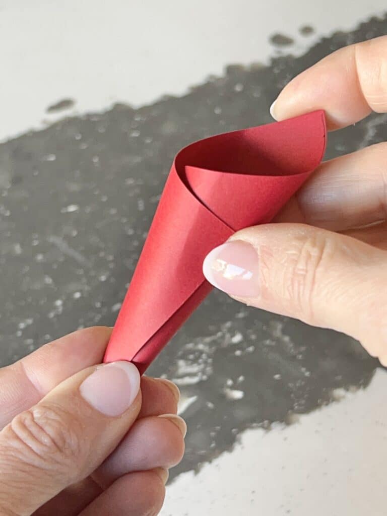 The square red paper twisted into a cone shape.