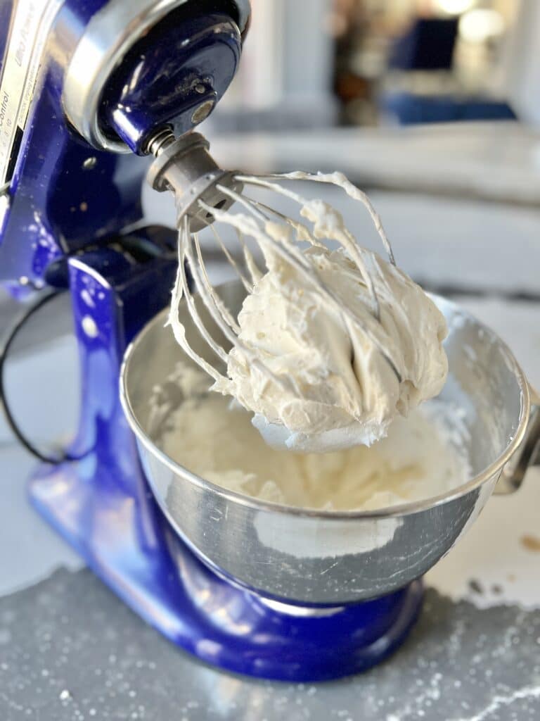 A stand mixer full of a cream cheese mixture.