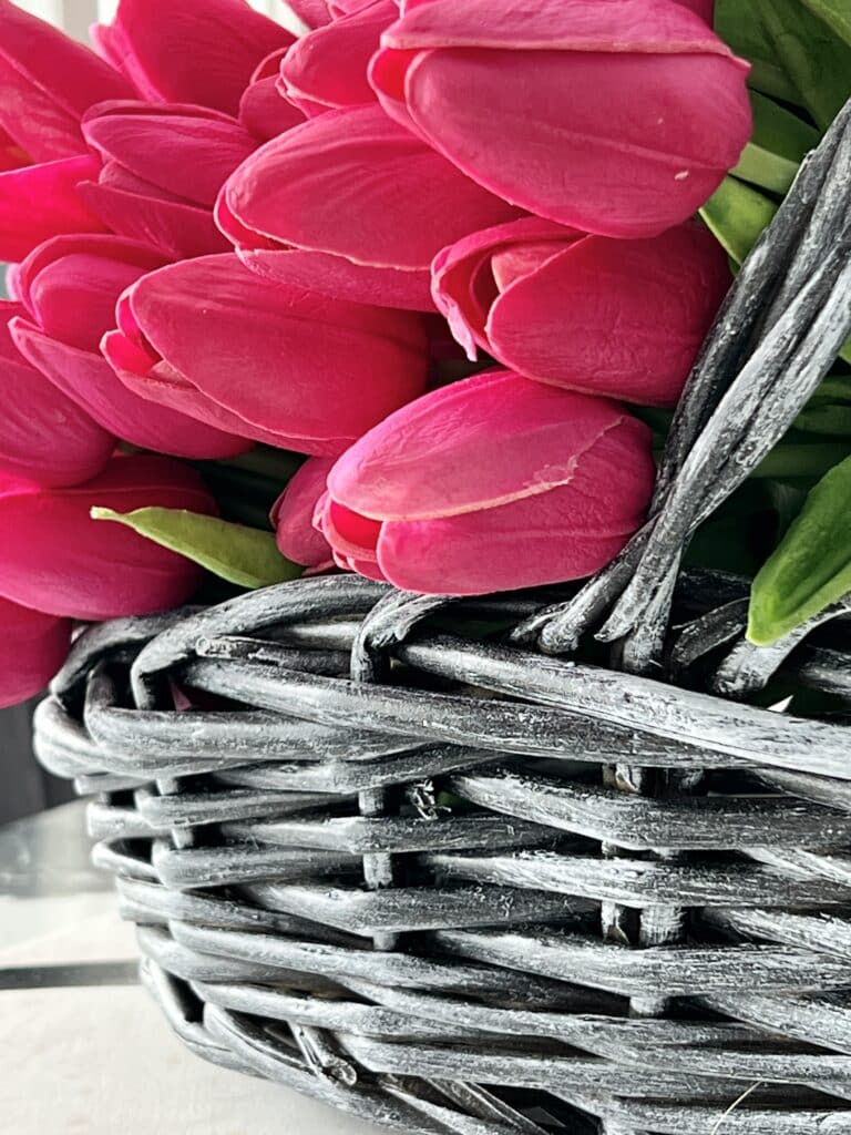 A painted wicker basket holding vibrant pink tulips.