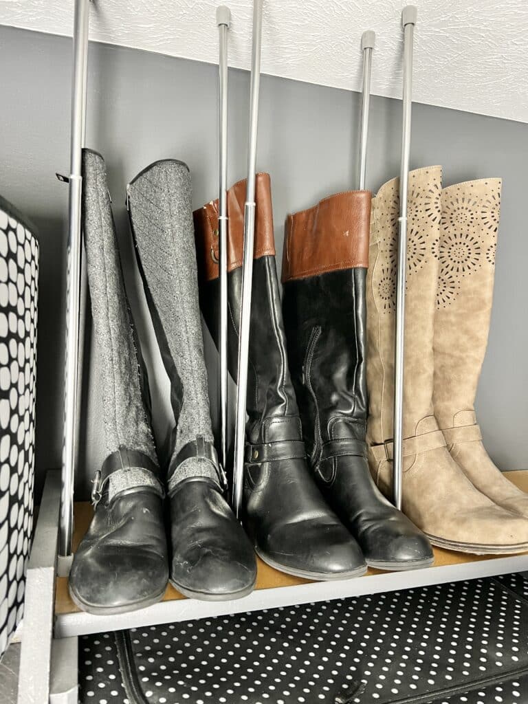 Vertically installed tension rods keeping tall boots organized in a closet.