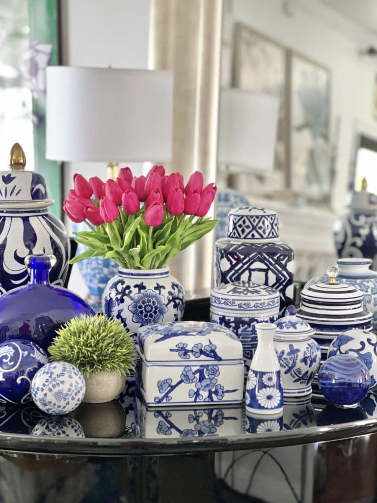 Pink faux tulips sitting in a sea of blue and white ceramics is a colorful spring home decor idea.