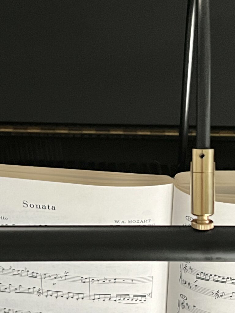 A piano light shining on a book of Sonatas.