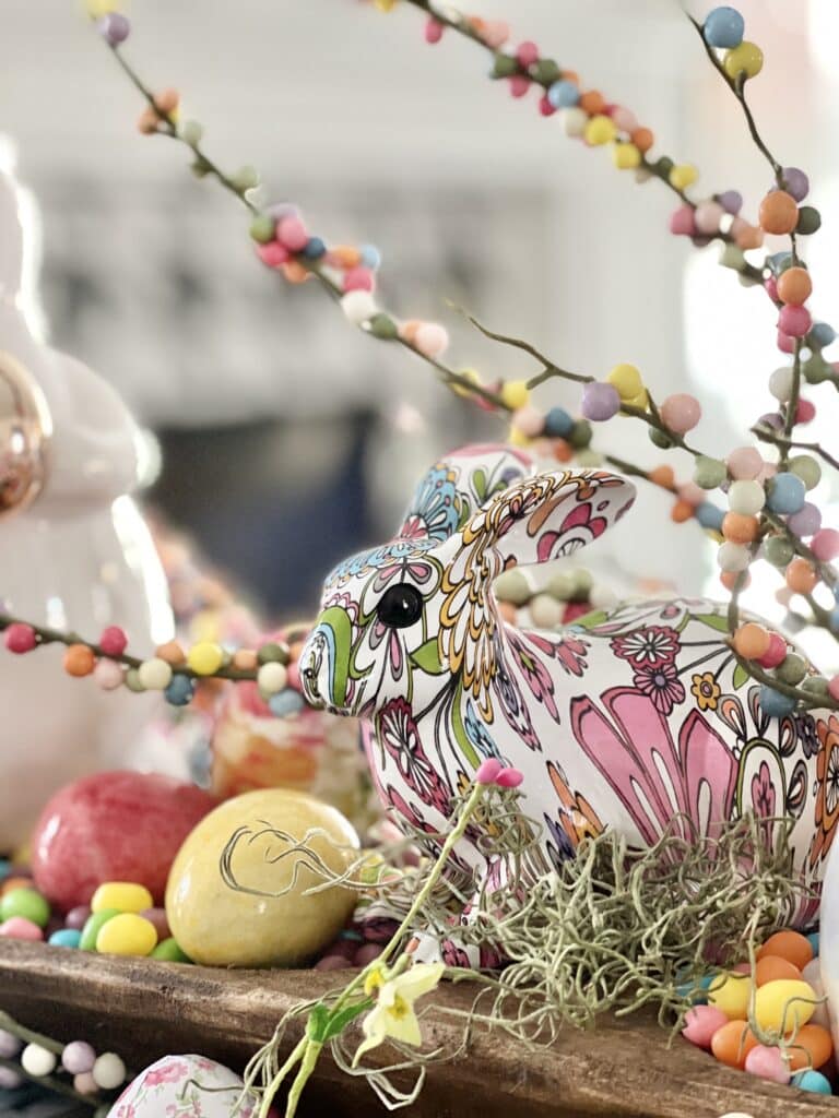 A colorful, patterned bunny nestled among marble Easter eggs and jelly beans is a great Easter decor idea for a table.