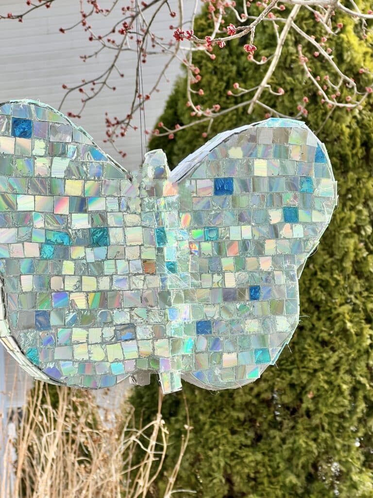 The butterfly shown hanging outdoors from a tree branch as garden space decor.